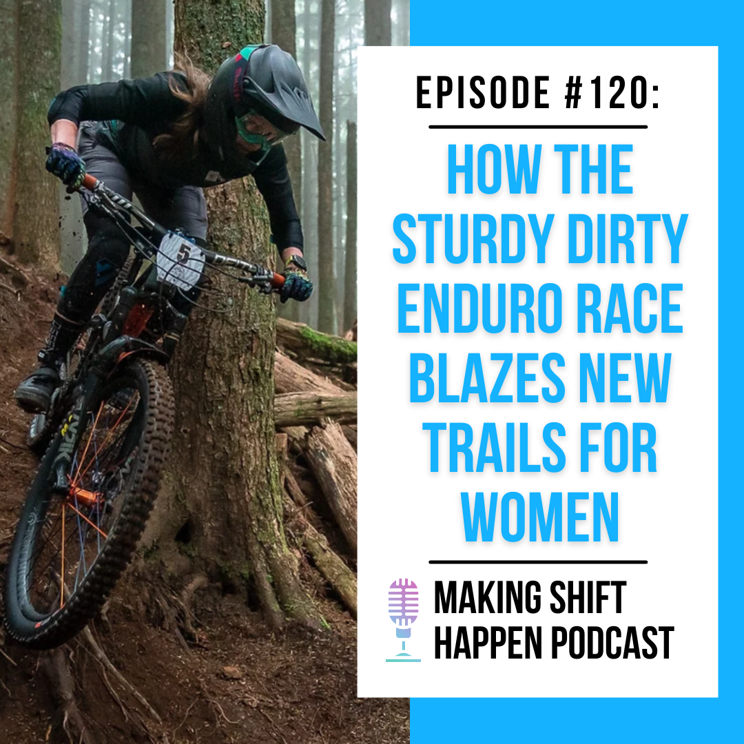 A mountain biker wearing grey shorts and a black long-sleeve jersey is racing down a tree-lined and root-covered trail in the Sturdy Dirty Enduro Race, wearing a full face helmet and bright turquoise and pink goggles while looking ahead and around the corner on the trail.